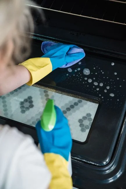 who-we-are Deux travailleurs nettoient les vitres d’un immeuble moderne en verre depuis une plateforme suspendue.